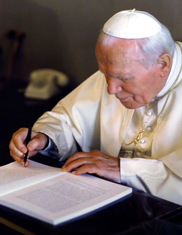 El santo Papa Juan Pablo II firma una de sus encíclicas
