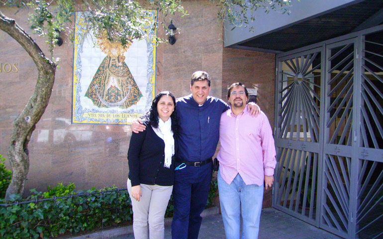David y Mariana, con el padre Óscar García, delante de la parroquia Virgen de los Llanos, en Madrid.