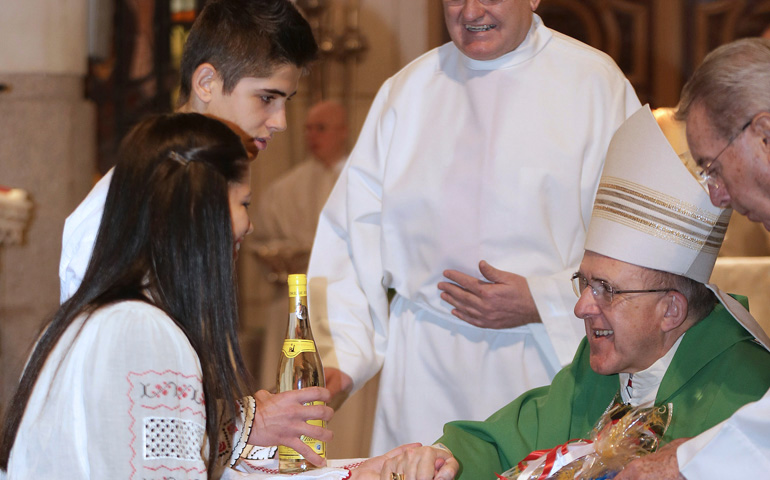 Monseñor Osoro con dos jóvenes rumanos durante una Misa en la parroquia madrileña de Nuestra Señora del Buen Suceso