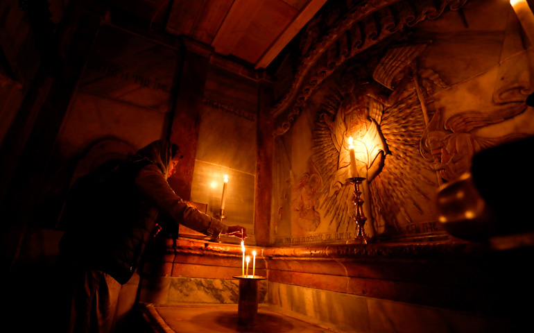 Una cristiana enciende una vela en el lugar donde se cree que se encuentra la tumba de Jesucristo, en el Edículo del Santo Sepulcro de Jerusalén