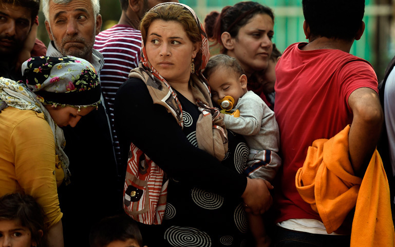 Una mujer, refugiada de Siria, madre, con su bebé en brazos, junto a otros refugiados, en un campo de refugiados en Presevo, Serbia, el 30 de agosto de 2015