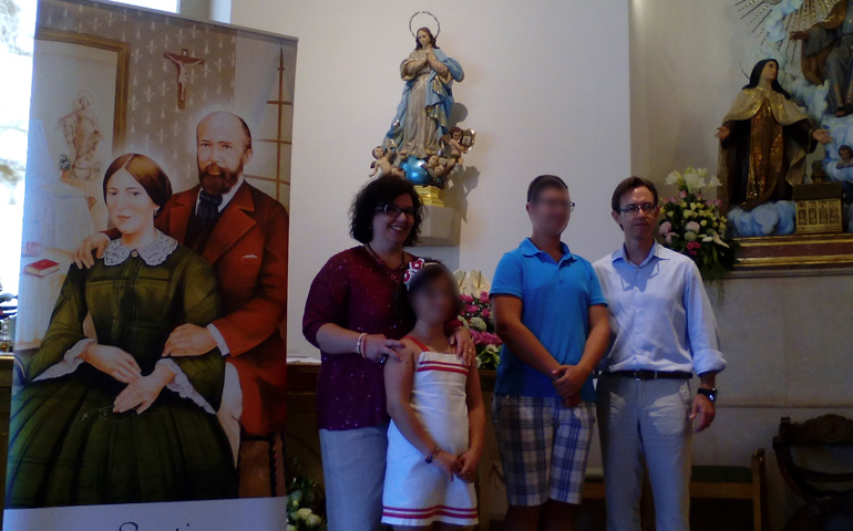 Carmen y su familia junto a una retrato de los padres de santa Teresa de Lisieux.