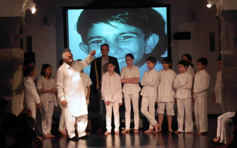 Ehsan Ullah Kahn, con niños de Génova en 2013. Detrás, foto de Iqbal Masih
