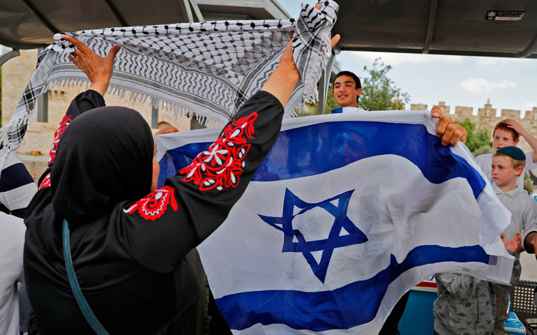 Una mujer muestra un pañuelo palestino frente a unos jóvenes israelíes, con su bandera nacional, en la puerta de Damasco, en Jerusalén