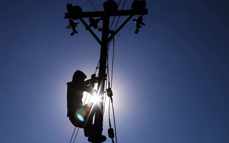 Foto de recurso de un trabajador encaramado a un poste de teléfonos
