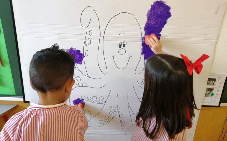 Dos niños de Infantil pintan uno de los juguetes de ensartar aro
