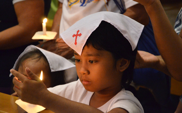 Dos hermanas sujetan las velas que les han sido entregadas como símbolo de la fe durante su Bautismo