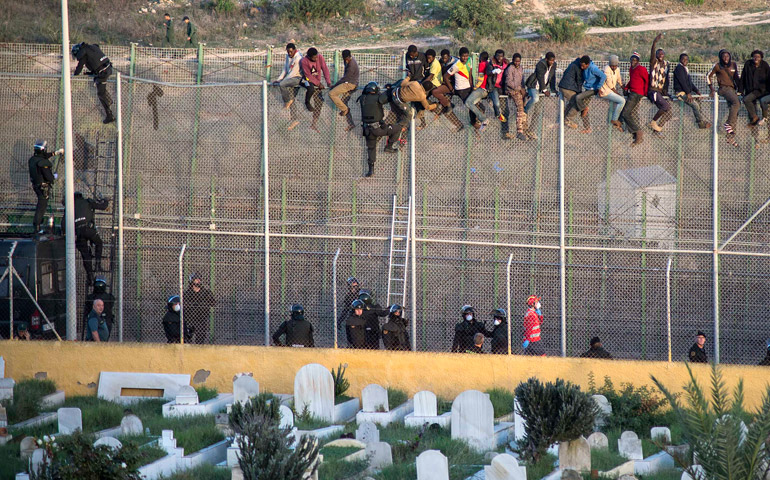 Un grupo de migrantes intenta cruzar la valla que separa Marruecos de España, en Melilla