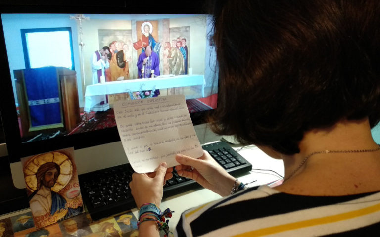 Una mujer reza la comunión espiritual durante la Misa televisada