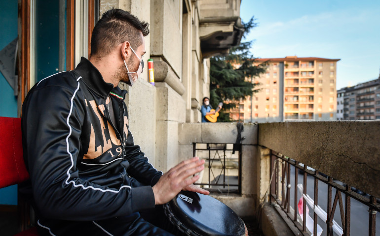 Unos jóvenes tocan instrumentos desde los balcones para animar a sus vecinos en Milán (Italia), el 13 de marzo