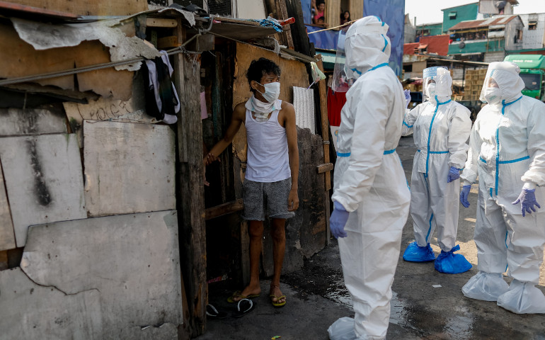 Personal sanitario pide a una persona sospechosa de infección de COVID-19 que vaya con ellos en una zona de chabolas de Manila (Filipinas), el pasado 15 de abril