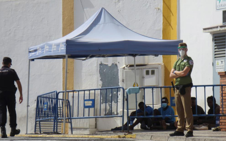 Un policía y un guardia de seguridad vigilan a un grupo de inmigrantes que han logrado saltar la valla en Melilla