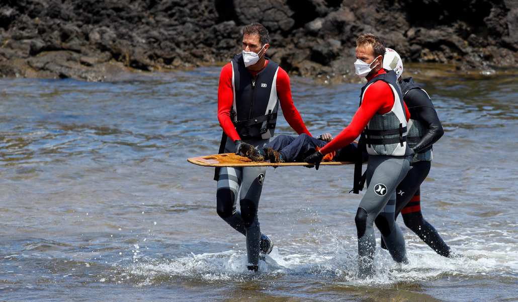 Dos operarios recogen el cuerpo de un migrante fallecido en Lanzarote el pasado mes de junio