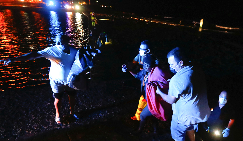 Varias personas ayudan a un migrante tras desembarcar en la playa del Castillo del Romeral, en la isla de Gran Canaria