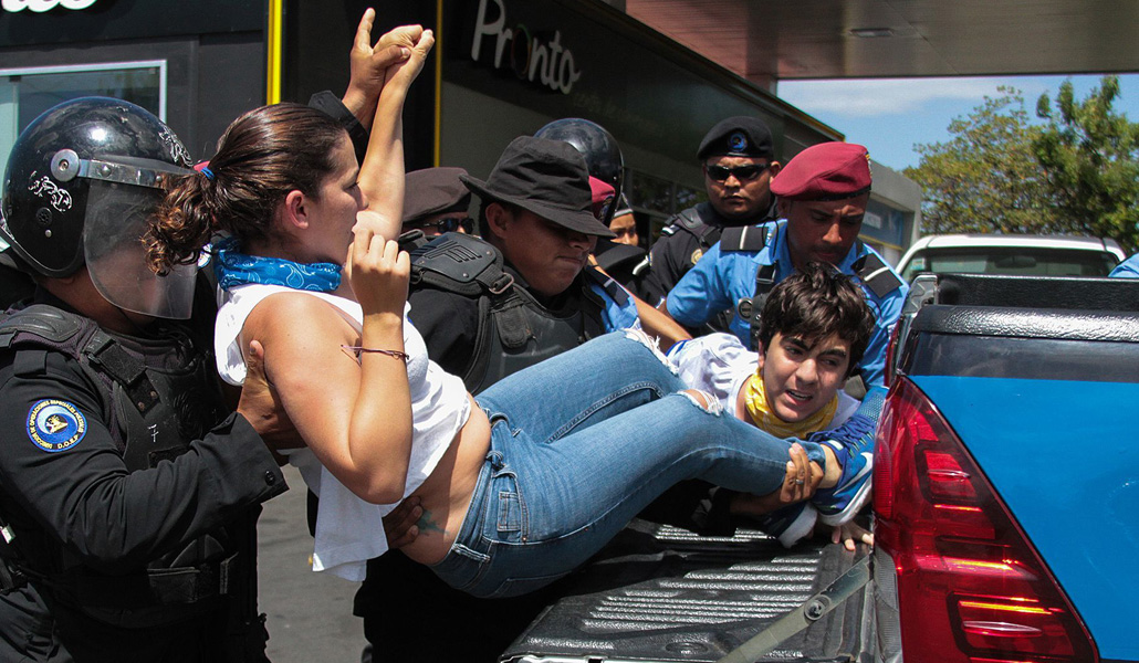 Agentes de la policía antimotines de Nicaragua arrestando a una manifestante