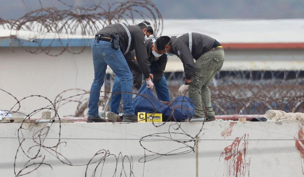 Policías ecuatorianos retiran el cuerpo de un recluso en el techo de un pabellón de la prisión Guayas 1 en Guayaquil