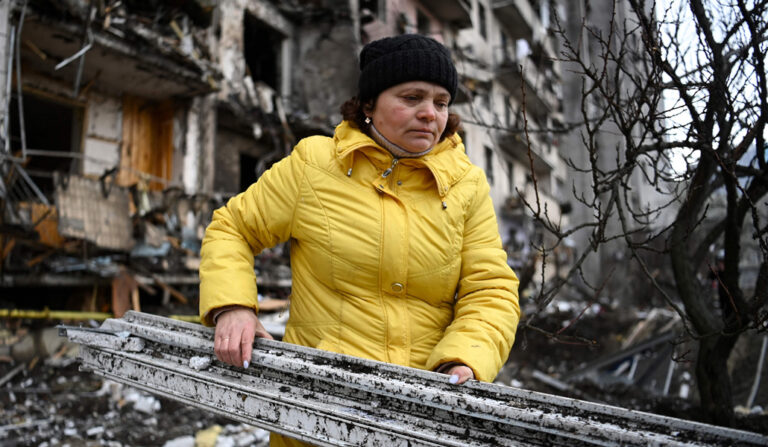 Una mujer limpia los restos de cascotes de un edificio a las afueras de Kiev, supuestamente dañado por un misil