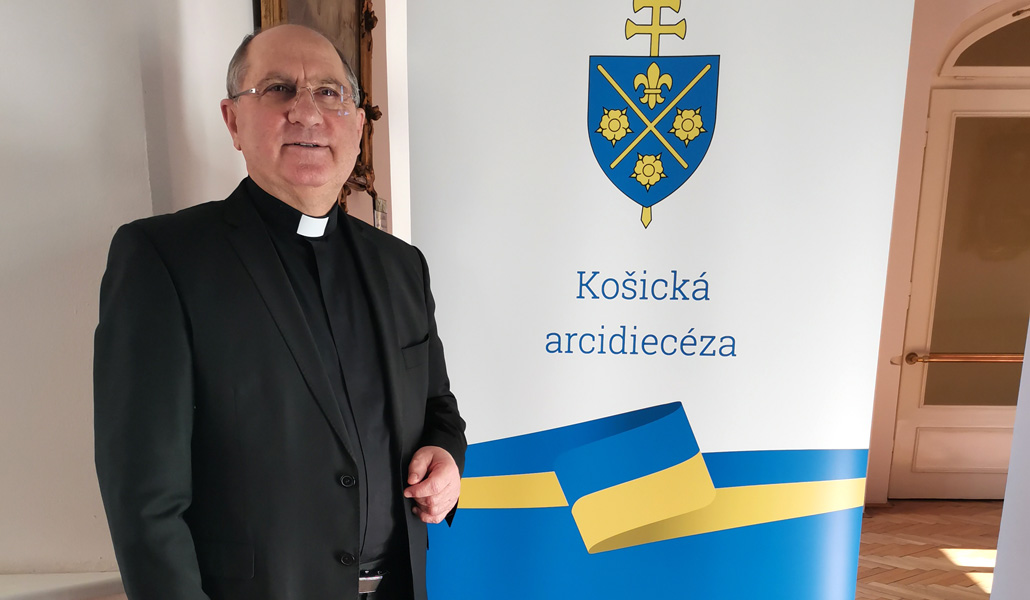 El arzobispo de Košice posa junto a un cartel que muestra la colaboración de la Iglesia con los refugiados ucranianos