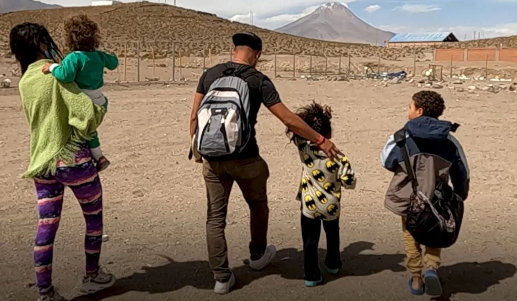 Una familia de migrantes en Colchane, con el paisaje del altiplano