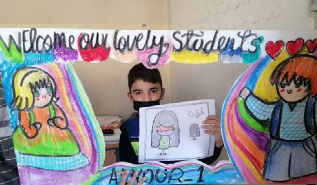 Un niño sirio tras el 'photocall' que les da la bienvenida a las aulas
