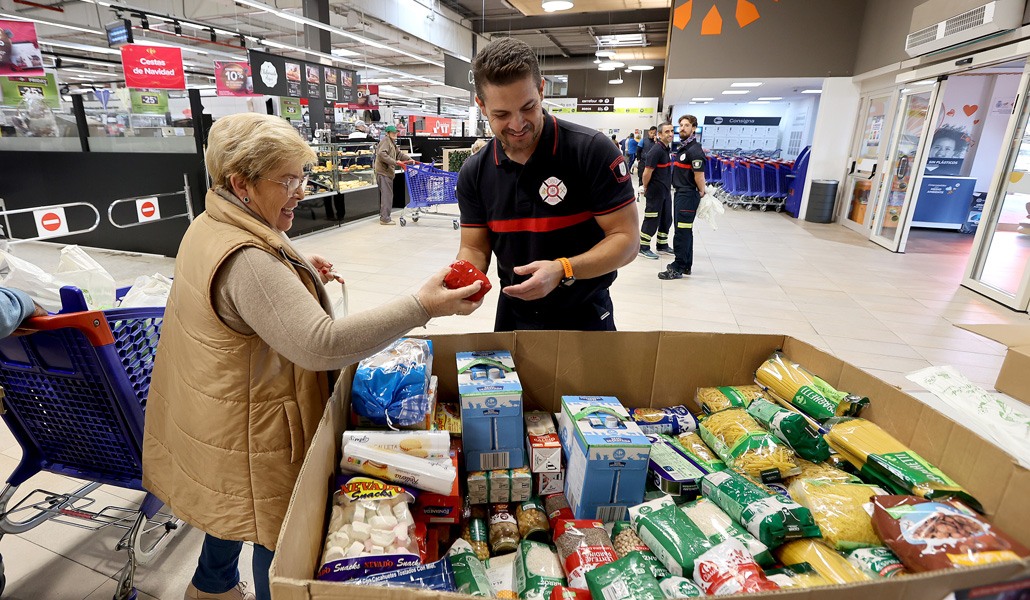 Una mujer entrega alimentos a un voluntario de FESBAL