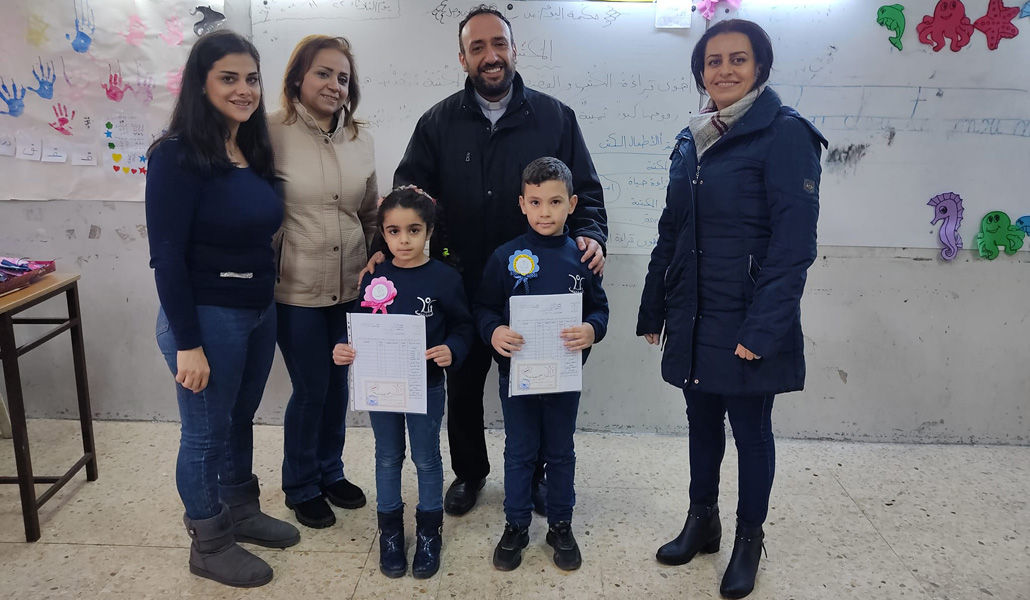 El padre Fadi Najjar con niños y maestras del colegio Al Inaya