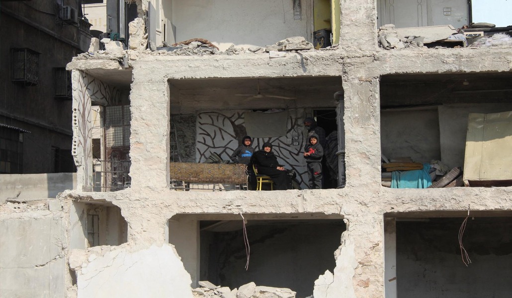Una mujer de Alepo con sus nietos dentro de una vivienda destrozada