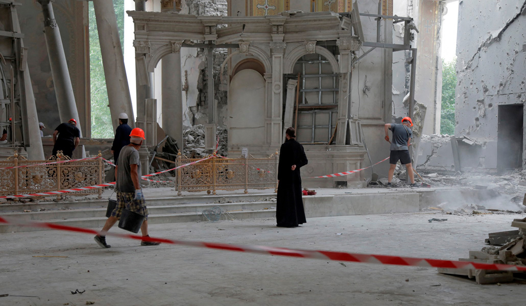 Unos voluntarios retiran los escombros mientras un sacerdote ortodoxo reza en la catedral de la Transfiguración dañada durante un ataque con misiles rusos, en Odesa, (Ucrania), el 23 de julio de 2023