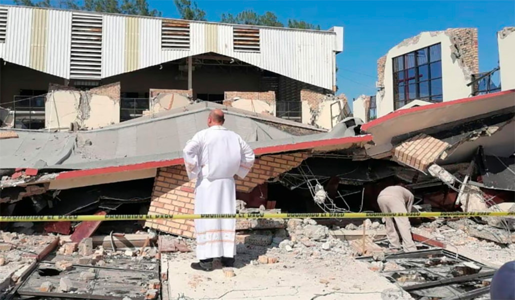 Un sacerdote en el exterior de la iglesia derruida