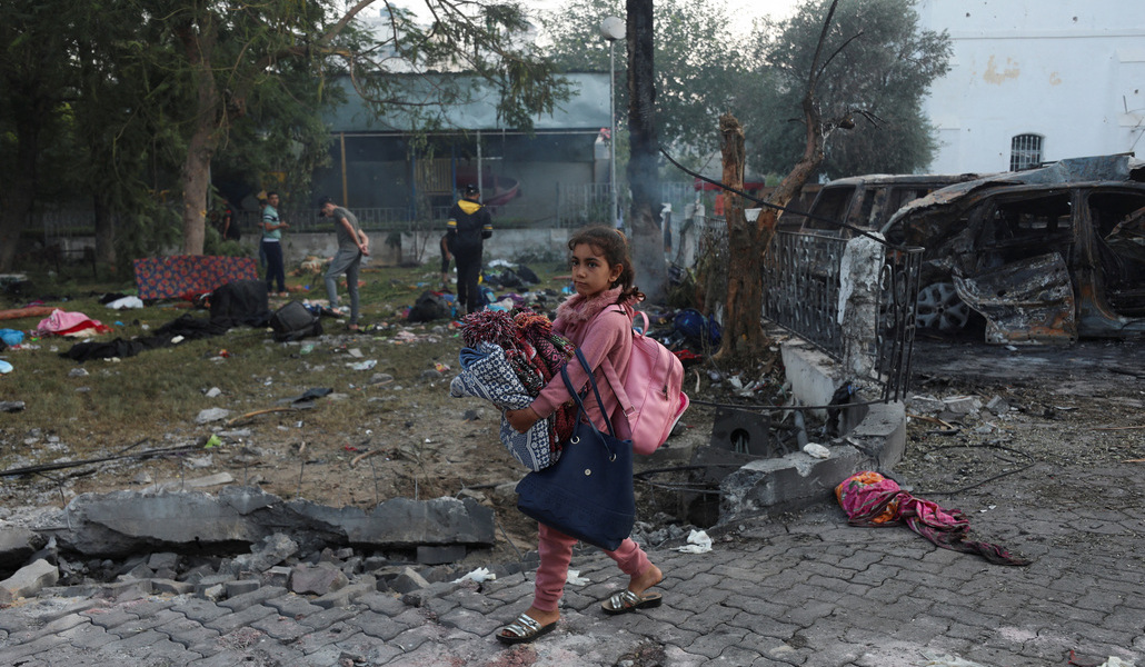 Niña camina entre coches quemados