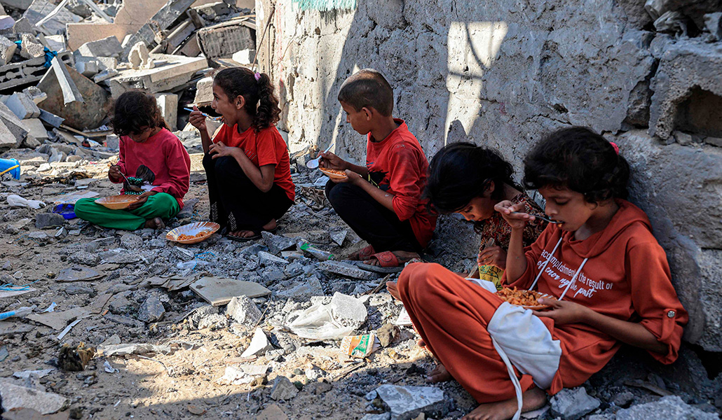 Unos niños comen en medio de las ruinas de la casa familiar destruida en un ataque israelí en Rafah, en el sur de la Franja de Gaza, el 7 de noviembre de 2023