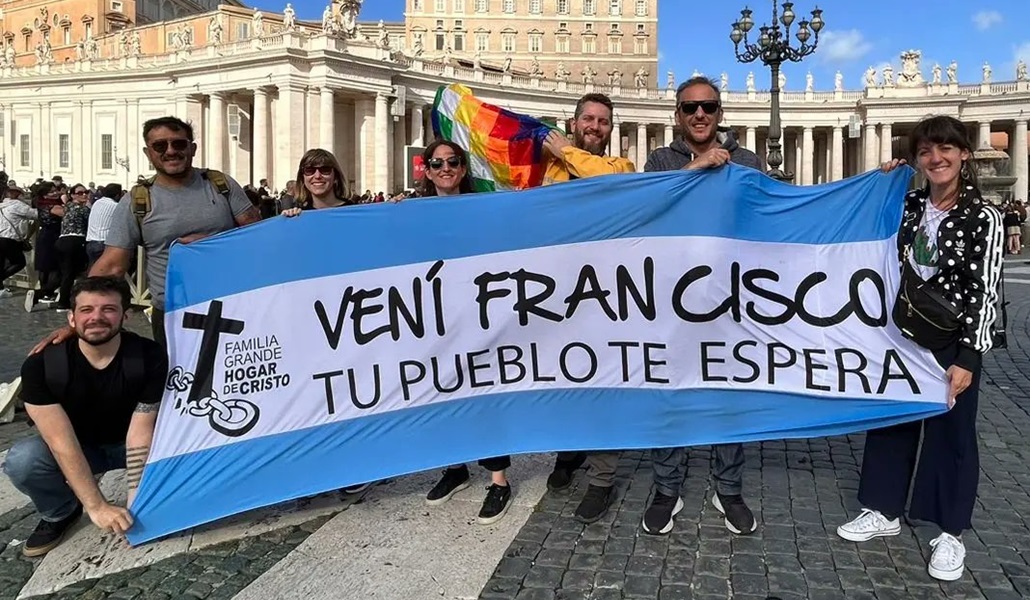 Peregrinos argentinos invitando con una bandera de su país al Papa a visitarlos