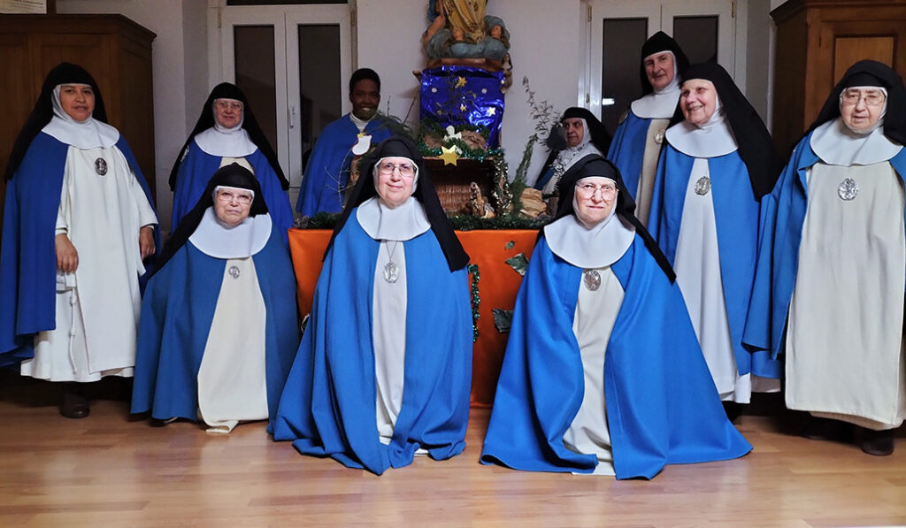Parte de la comunidad posa con uno de los belenes que llenan su casa estos días.