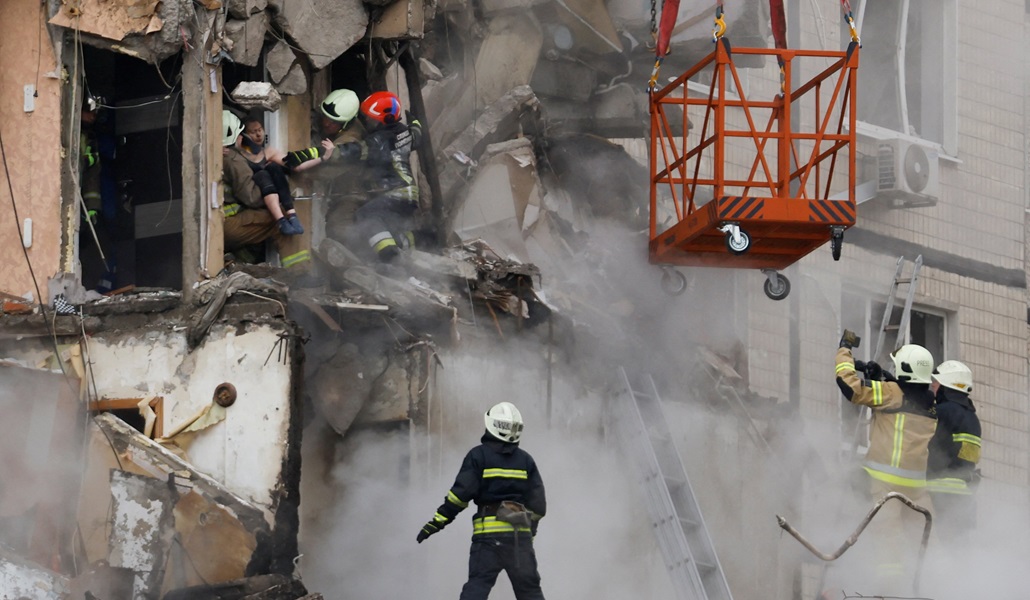 Personal de emergencia evacua a una persona el 15 de enero de 2023, de un edificio de apartamentos que fue fuertemente dañado por un ataque de misiles rusos en Dnipro, Ucrania. Grupos católicos afirman que proporcionar suministros a los ucranianos se ha vuelto «extremadamente peligroso» tras el ataque con misiles y un voluntario católico perdió una pierna al entregar alimentos en la asediada región de Donbás
