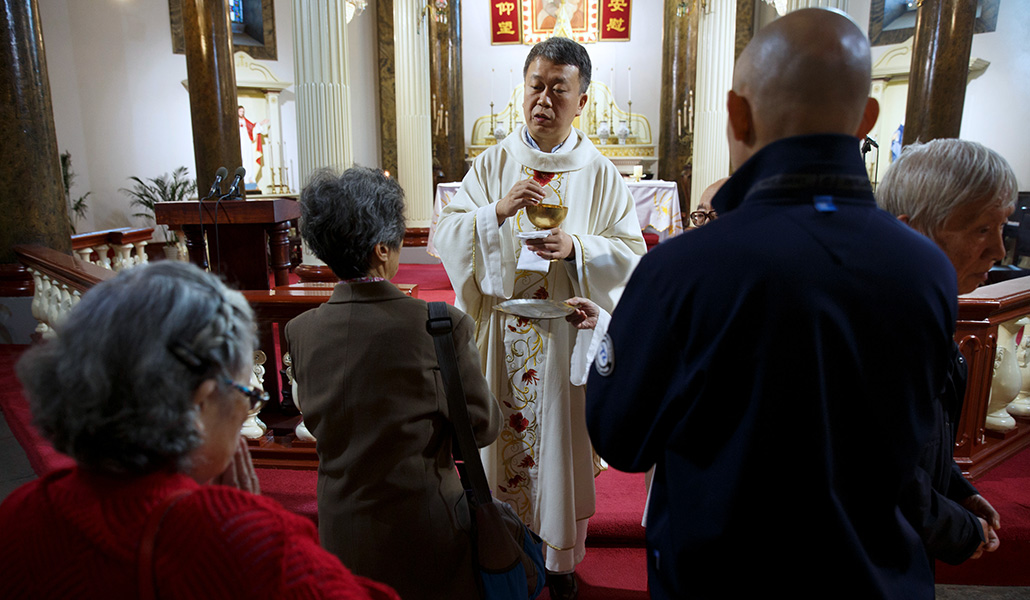 Un sacerdote reparte la comunión a los fieles en una iglesia de Pekín