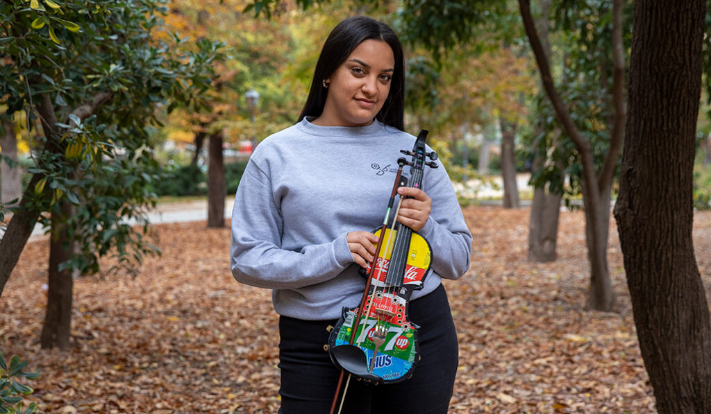 Cristina con uno de los violines construidos con materiales de desecho de la orquesta