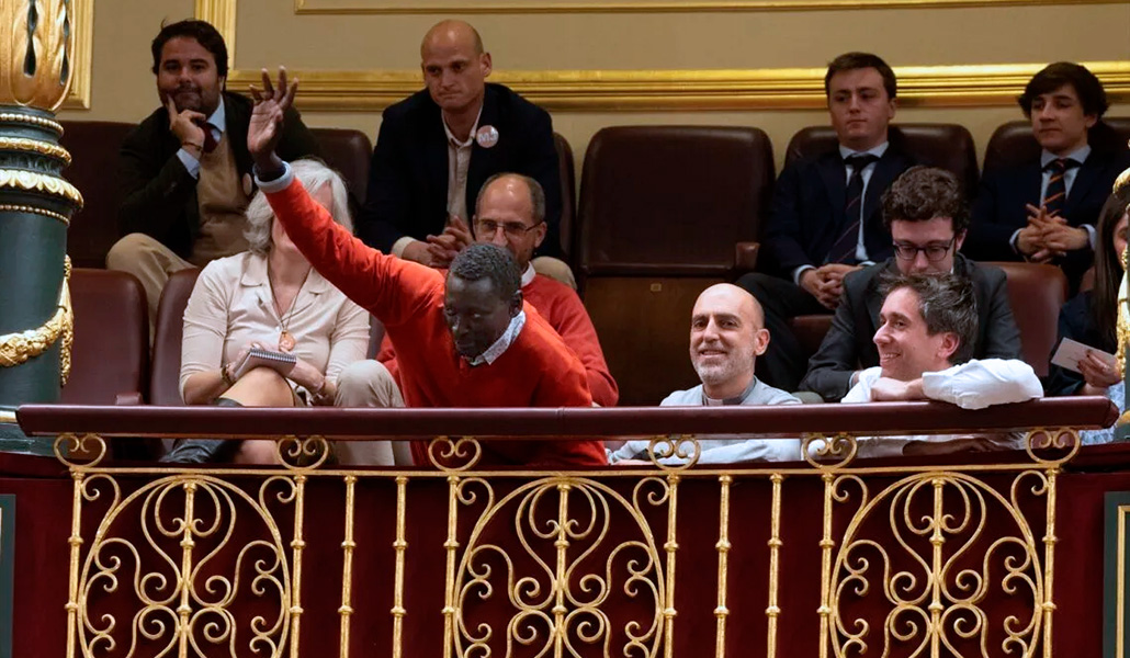El impulsor de la ILP Agustín Ndour durante una sesión plenaria en el Congreso junto a Xavier Gómez (al lado), director del Departamento de Migraciones de la CEE y Jorge Serrano (detrás), coordinador del Partido Por un Mundo más Justo y representante de la ILP