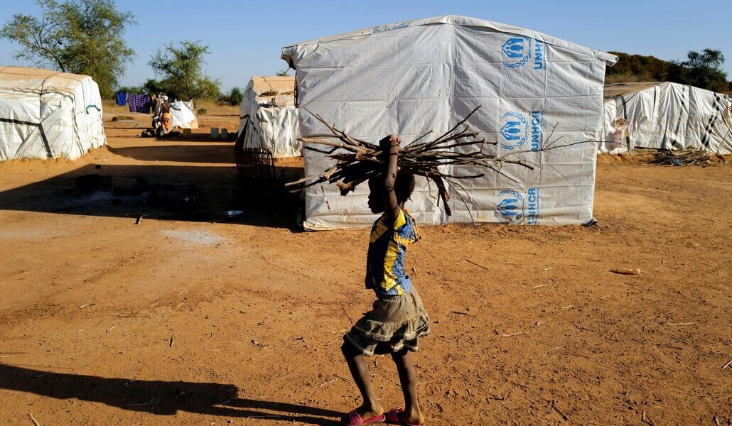 Una niña lleva leña en la cabeza en un campo de desplazados del Sahel