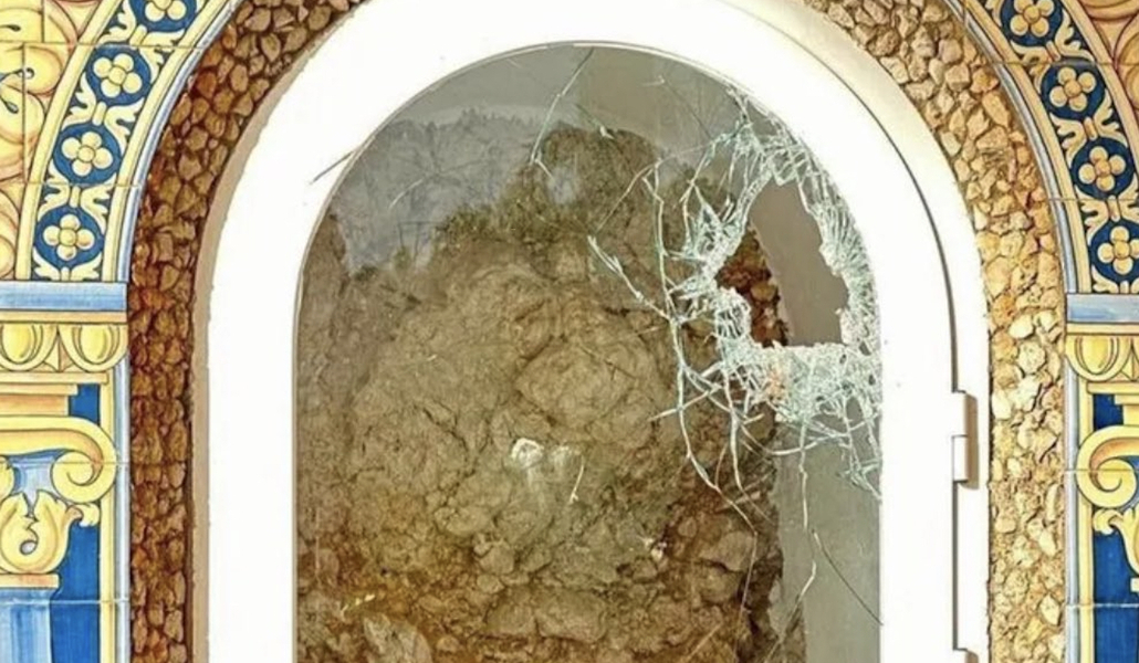 Cristal con un agujero detrás del que se ve vacía la hornacina que sufrió la profanación