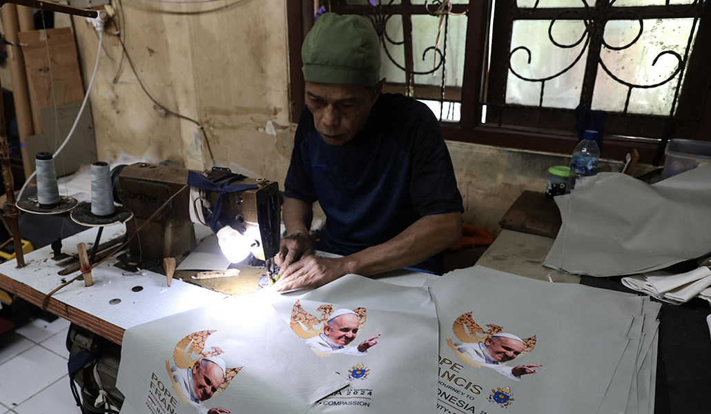 Una trabajadora musulmana cose bolsas con la imagen del Papa Francisco antes de su visita a Indonesia