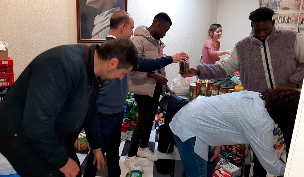 Voluntarios reparten comida a inmigrantes en los locales de la parroquia