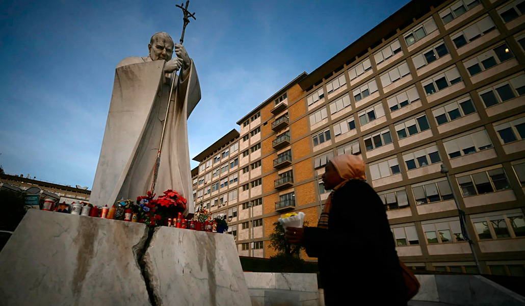 Una mujer ante la estatua de san Juan Pablo II fuera del Hospital Gemelli, el 15 de febrero