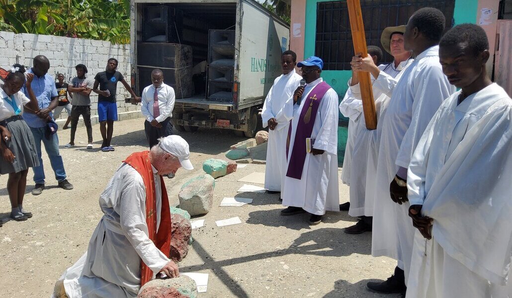 Oblatos de San Francisco de Sales (dos misioneros y uno local) con varios acólitos durante una oración al aire libre en Cité Soleil, Haití