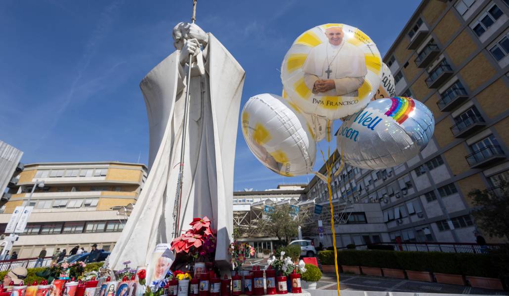 Peregrinos rezan en la fachada exterior del hospital Gemelli de Roma con globos por la recuperación del Papa