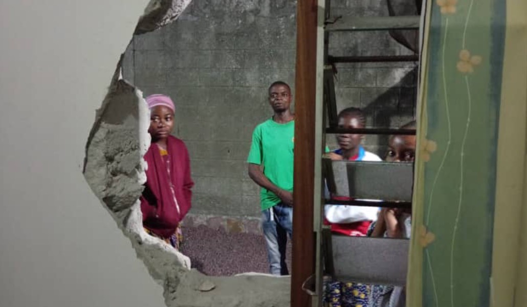 Vecinos miran por el boquete por el que entraron los criminales.