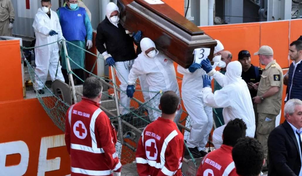 Varios operarios bajan a tierra en el puerto italiano de Palermo el ataúd de un migrante muerto