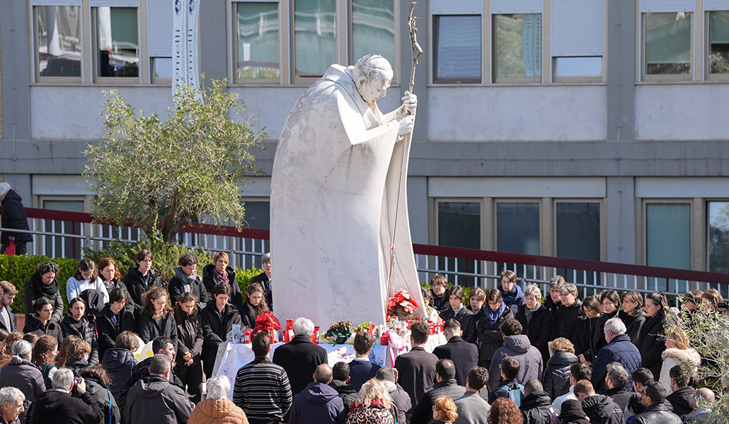 Un grupo de fieles reza el pasado domingo en torno a la escultura de san Juan Pablo II ante el Gemelli