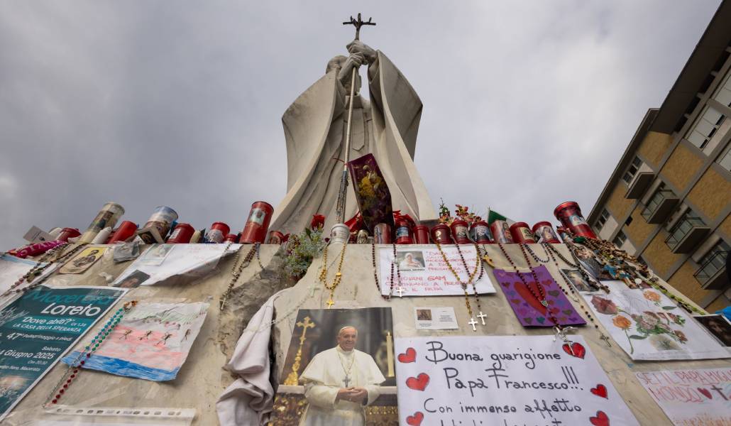 Velas, rosarios y oraciones depositados en la estatua del san Juan Pablo II en el exterior del hospital donde se encuentra hospitalizado Francisco