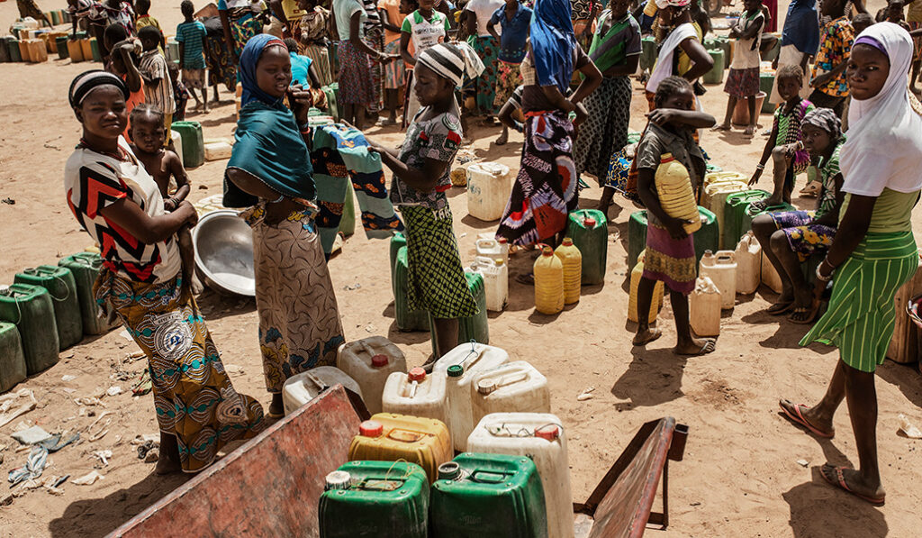 Mujeres y niñas esperan pacientemente el reparto del agua en el campo de desplazados de Barsalogho, en la región centro norte de Burkina Faso