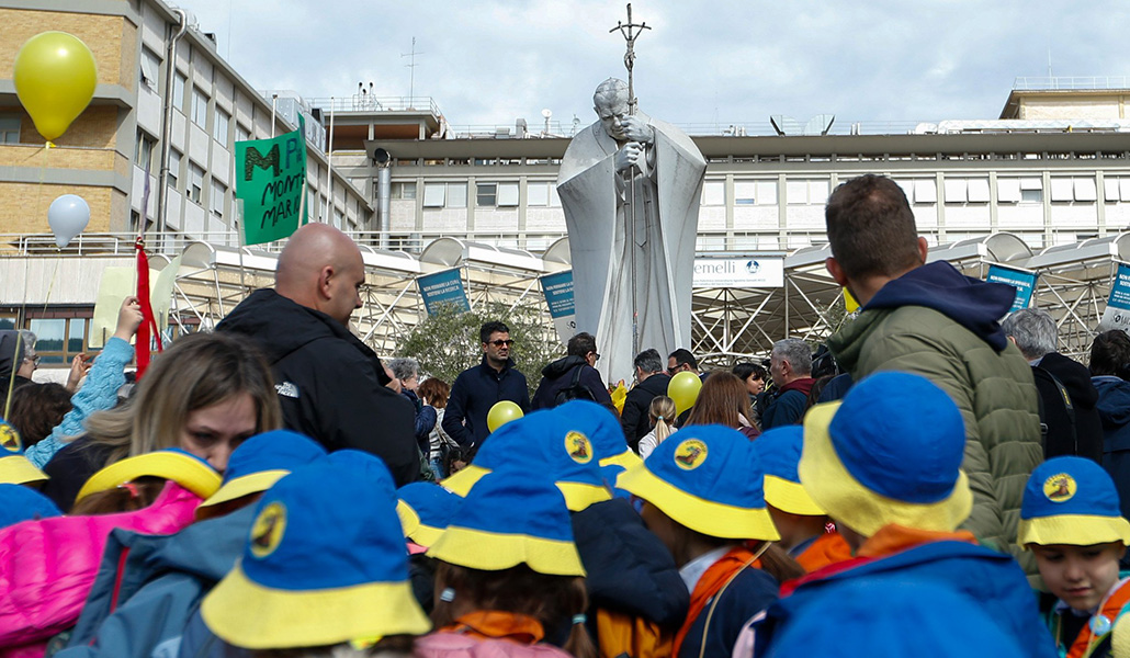 Un grupo de scouts rezan en la escultura de Juan Pablo II ante el Hospital Gemelli